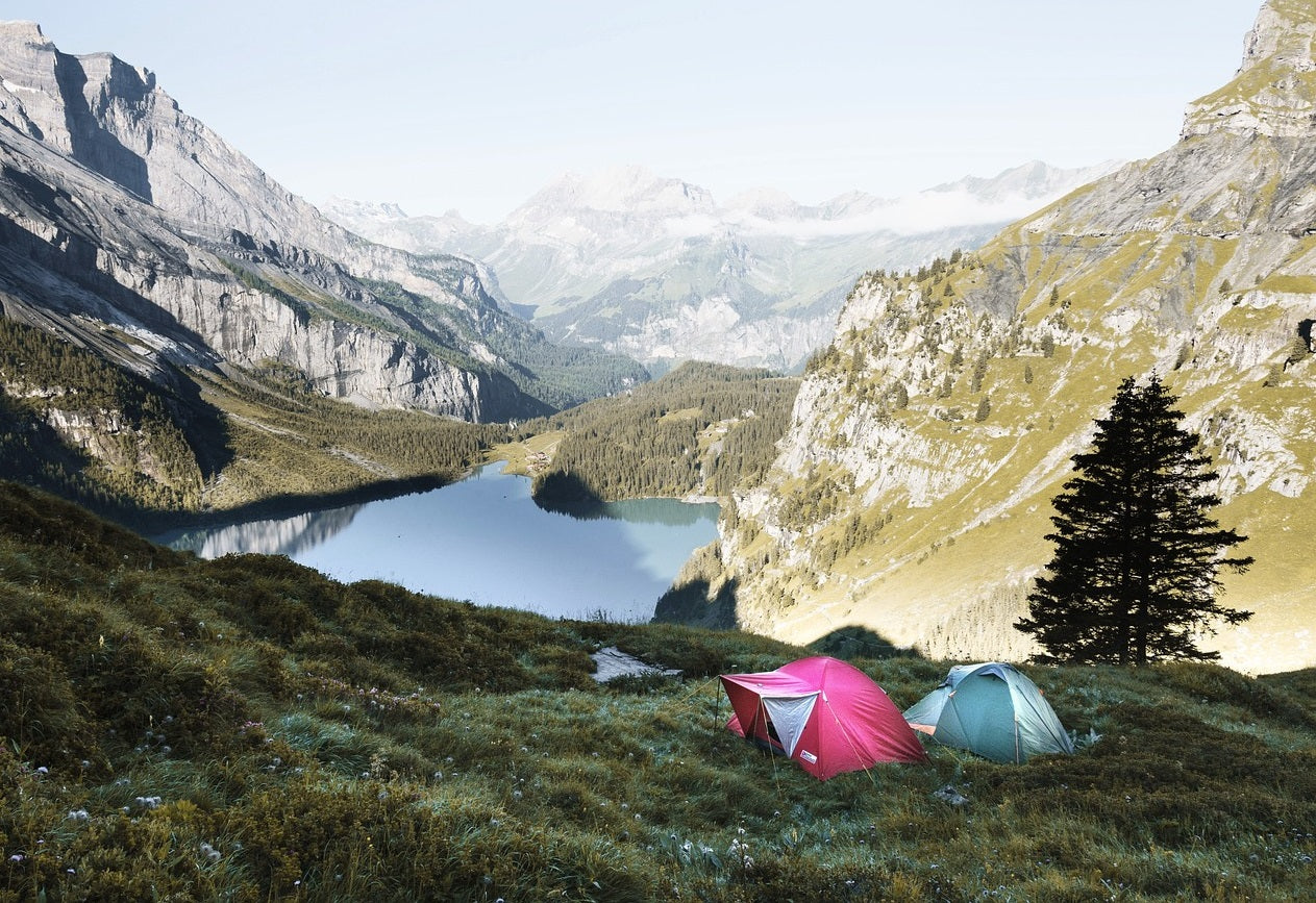 Two tents pitched with a view of a lake and mountains