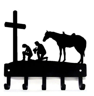 A man and woman kneeling at the cross with a horse beside them