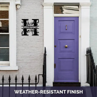 A purple front door with a metal H with vines scrolling around it and the name HARRISON. 