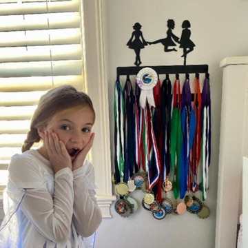 A girl excited to see her Irish dancer medal hanger filled with ribbons and medals.