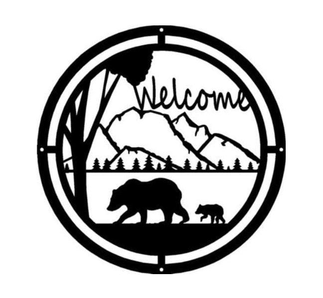 A round sign made of metal, with a bear and cub walking through the mountains. The sign says welcome.
