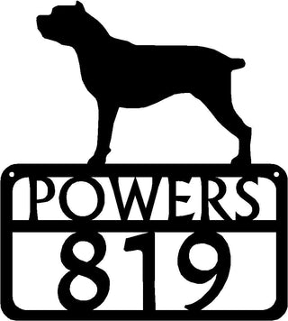 An address sign with a dog on top, with a name and house numbers cut from metal.