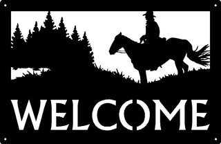A black rectangle with laser cut detail of a cowboy on a horse with trees in the background. The wording says WELCOME.