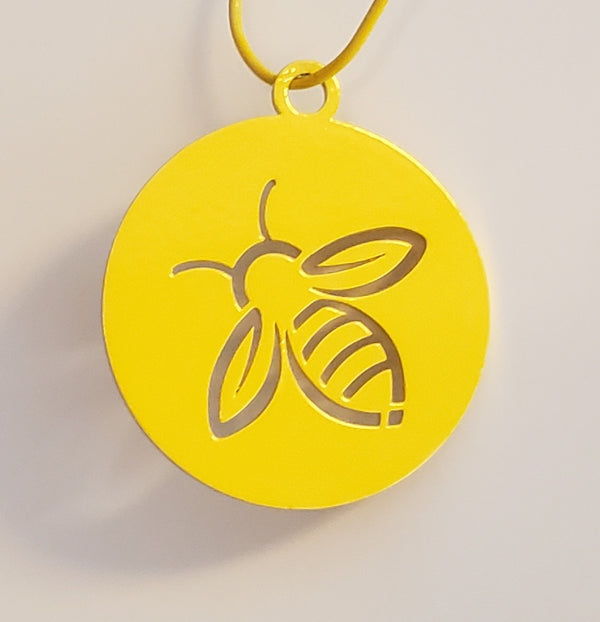 A yellow metal disc with a cut out design of a honey bee. 
