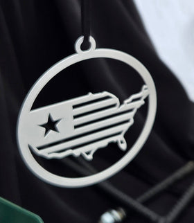 Metallic emblem with a star and a design resembling a map of the United States on a dark background.