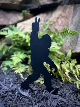 Bigfoot ground stake giving a peace sign as he walks through the ferns