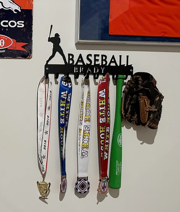 A medal hanger with the design of a baseball batter. The top says Baseball and the name Brady is cut into the bar. It has 10 hooks.