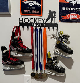 A 10-hook hockey medal hanger customized with a name Brady in the bar.