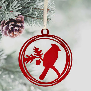 Red ornament in a christmas tree with a cut out design of a cardinal bird