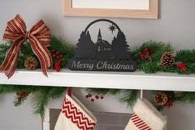 Decorative Christmas mantel with a bow, garland, and 'Merry Christmas' sign.