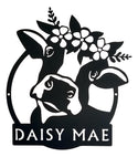 Black cutout of a cow with flowers and 'DAISY MAE' text on a white background