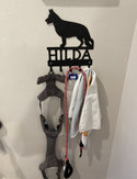 A leash hanger with the design of a German Shepherd dog cut from the metal and the name Hilda cut out the metal.