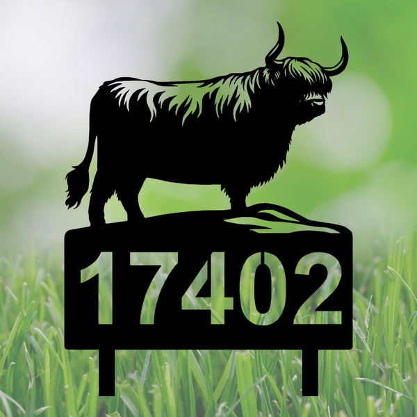 A black metal yard sign featuring a Highland cow silhouette on top of a rectangular base with the number 17402, shown against a blurred green grass background.