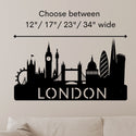 Black London skyline wall decal with silhouettes of famous landmarks and the word 'LONDON' at the bottom, shown on a beige wall above a sofa. Text above reads 'Choose between 12" / 17" / 23" / 34" wide' with a measurement arrow.