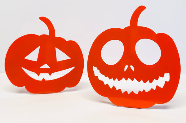 Two orange paper jack-o'-lanterns with white faces on a white background