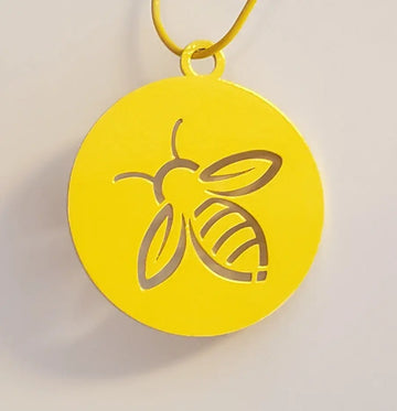 A yellow metal disc with a cut out design of a honey bee. 
