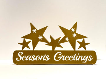 Decorative sign with stars and 'Season's Greetings' text on a beige background