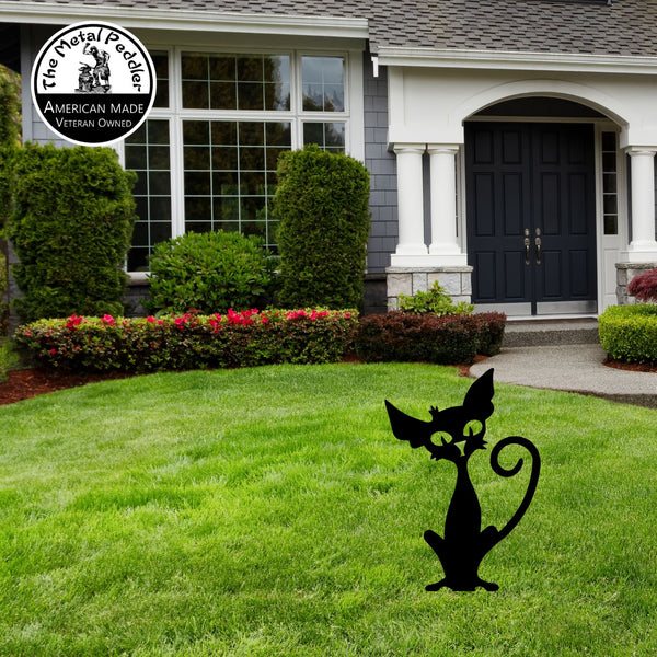 Metal cat sculpture on a lawn in front of a house . Halloween.