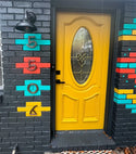 A yellow door with copper house numbers on the wall