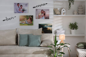 Living room with a beige sofa, decorative pillows, and a shelf with books and plants.