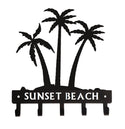 Palm Tree Silhouettes cut from steel, coated black, with 5 hooks for hanging keys. Has the words SUNSET BEACH cut from the hook bar.
