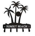 Palm Tree Silhouettes cut from steel, coated black, with 5 hooks for hanging keys. Has the words SUNSET BEACH cut out of the bar.