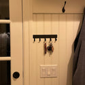 A plain metal glat bar with 5 hooks for hanging keys.