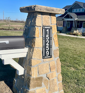 Stone mailbox post with house numbers in a residential area