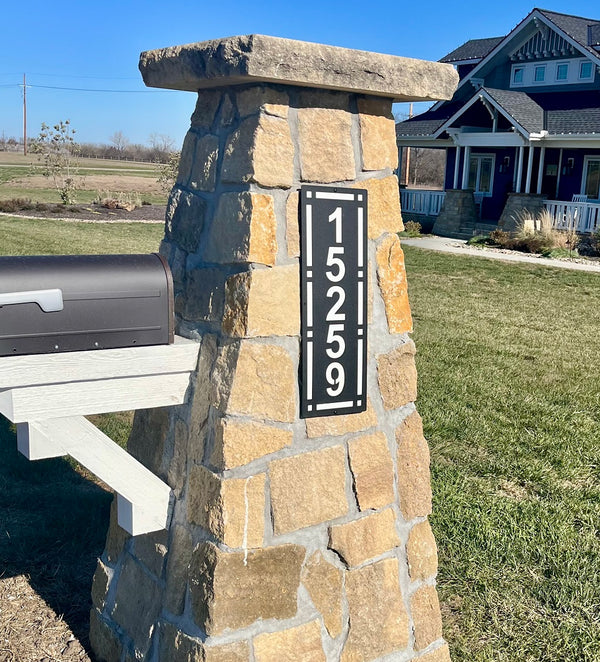 Stone mailbox post with house numbers in a residential area