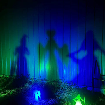 Silhouettes of witches against a wall with colorful light projections.