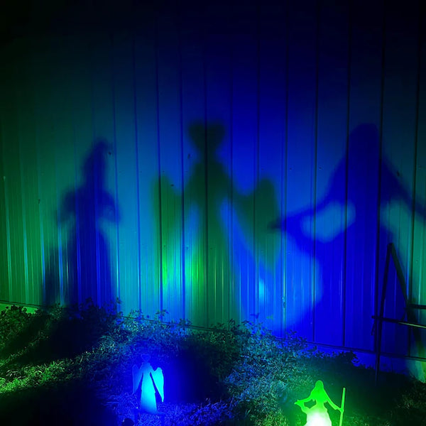 Silhouettes of witches against a wall with colorful light projections.