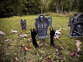Graveyard scene with tombstones and hands emerging from the ground, surrounded by trees and grass.